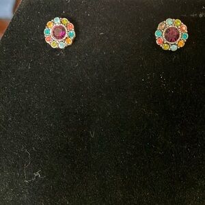 Purple stone surrounded by multicolored stones.  Pierced. 1/2”